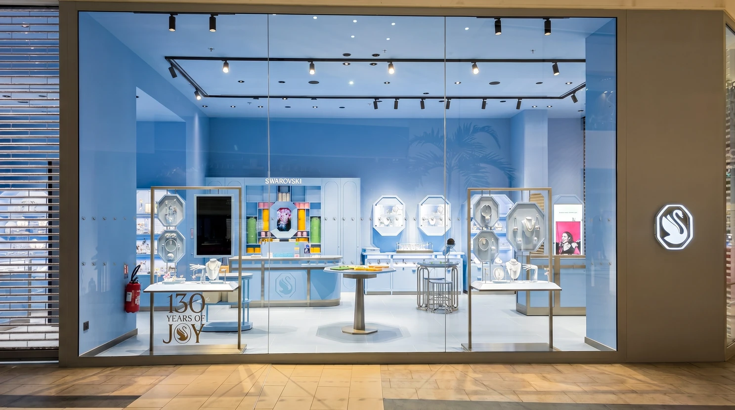 Façade vitrée d'une boutique Swarovski en centre commercial, célébrant ses 130 ans