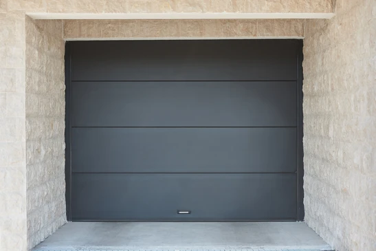 Façade extérieure résidentielle moderne avec porte de garage sectionnelle grise à fenêtres rectangulares