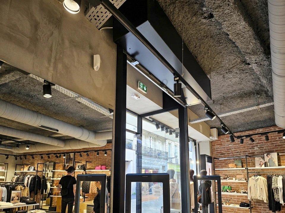 Scène d'atelier avec mains d'artisan travaillant sur surface quadrillée transparente, manipulation précise d'outils de découpe ou gravure